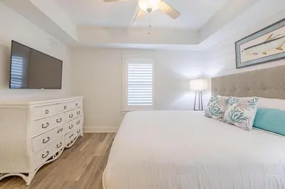 a bedroom with a bed with a television and a dresser at Calypso 3-903 - Emerald Getaway in Panama City Beach