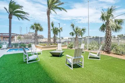 a group of chairs sitting on a lawn with palm trees at Calypso 3-903 - Emerald Getaway in Panama City Beach