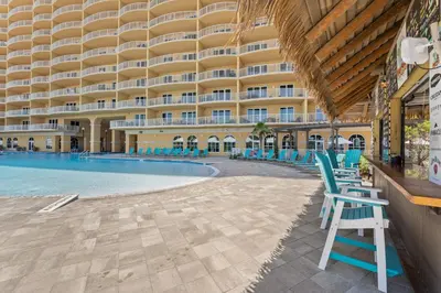 a large building with a swimming pool and blue chairs at Calypso Resort Tower 3 Unit 711 in Panama City Beach