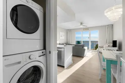 a kitchen and living room with a washer and dryer at Seychelles 1302 by InJoy Vacations in Panama City Beach