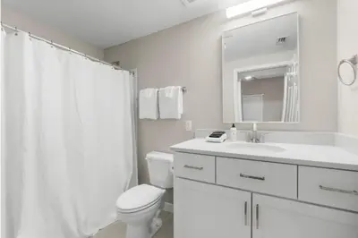 a white bathroom with a toilet and a sink at Seychelles 1302 by InJoy Vacations in Panama City Beach