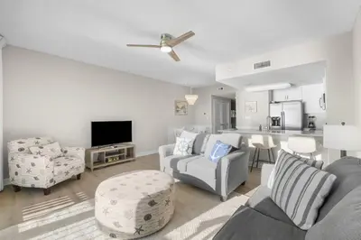 a living room with a couch and chairs and a kitchen at Seychelles 1302 by InJoy Vacations in Panama City Beach