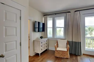 a bedroom with a dresser and a chair and windows at Green Wave in Inlet Beach