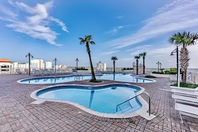 a large swimming pool with palm trees in a resort at Remodeled 3BD plus Bunks! Low Floor Family Beach Resort! 5 Pools! by Dolce Vita Getaways PCB in Panama City Beach