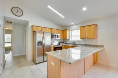 a kitchen with wooden cabinets and a stainless steel refrigerator at 1 Mi to Beach Family-Friendly Home in PCB! in Panama City Beach