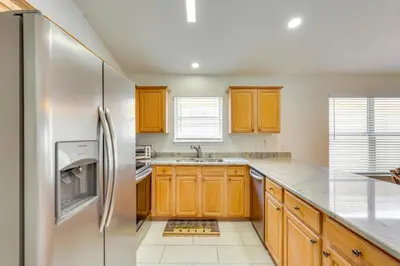 a kitchen with wooden cabinets and a stainless steel refrigerator at 1 Mi to Beach Family-Friendly Home in PCB! in Panama City Beach