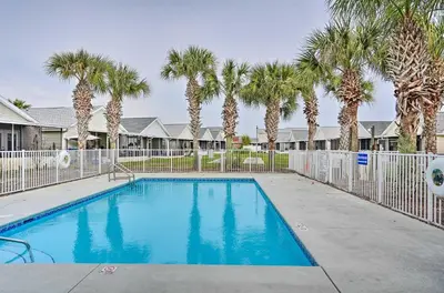 a swimming pool with palm trees and a fence at 1 Mi to Beach Family-Friendly Home in PCB! in Panama City Beach