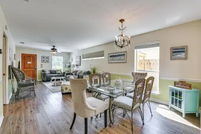 a dining room and living room with a table and chairs at Breezy PCB Vacation Rental with Lanai, Walk to Ocean in Panama City Beach