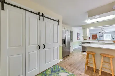 a kitchen with white doors and a counter and two stools at Breezy PCB Vacation Rental with Lanai, Walk to Ocean in Panama City Beach
