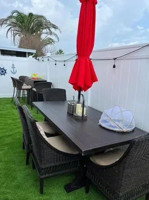 a black table with chairs and a red umbrella at Vacation Home near Beach and Waterpark! in Panama City Beach