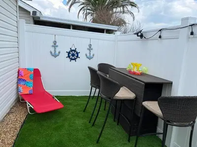 a patio with a table and chairs on grass at Vacation Home near Beach and Waterpark! in Panama City Beach