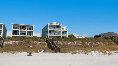 a house on top of a beach next to a building at Turtle Beach - 55 Nature Way #100 in Santa Rosa Beach