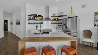 a kitchen with a wooden counter and orange stools at Turtle Beach - 55 Nature Way #100 in Santa Rosa Beach