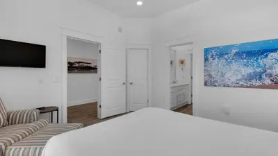a white bedroom with a bed and a tv at Turtle Beach - 55 Nature Way #100 in Santa Rosa Beach