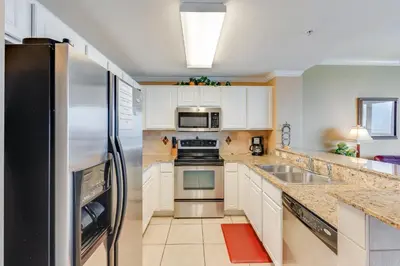 a kitchen with white cabinets and a stainless steel refrigerator at Calypso Resort Serenity 1 in Panama City Beach