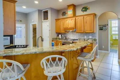 a kitchen with wooden cabinets and bar stools at Pet-Friendly Panama City Beach Home Near Beaches! in Panama City Beach