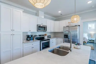 a kitchen with white cabinets and a stainless steel refrigerator at Sand's Hideaway in Panama City Beach