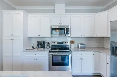 a kitchen with white cabinets and a stove top oven at Sand's Hideaway in Panama City Beach