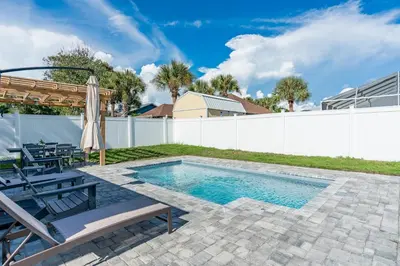 a swimming pool in a yard with a white fence at Sand's Hideaway in Panama City Beach
