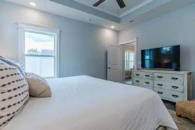 a bedroom with a white bed and a tv on a dresser at Sand's Hideaway in Panama City Beach