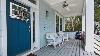 a front porch with a blue door and wicker chairs at Seagrove Serenity in Santa Rosa Beach