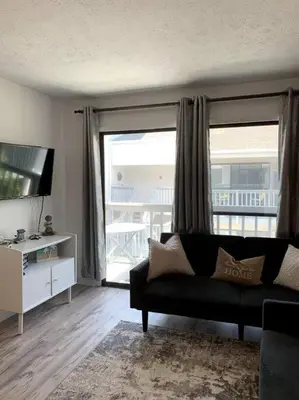a living room with a couch and a large window at FullyRenovated 1 min walk2 beach.5min to peir park in Panama City Beach