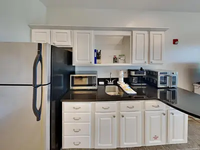a kitchen with white cabinets and black appliances at Inn At Seacrest 303 - Seaside Sunrise in Rosemary Beach