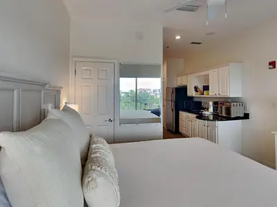 a white bedroom with a bed and a kitchen at Inn At Seacrest 303 - Seaside Sunrise in Rosemary Beach