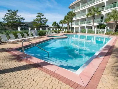 a swimming pool with chairs and a building at Inn At Seacrest 303 - Seaside Sunrise in Rosemary Beach