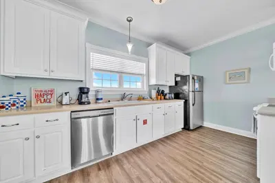 a kitchen with white cabinets and a refrigerator at Summer Towne Cottages #8 - Sea-Questered in Panama City Beach