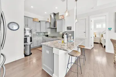 a kitchen with white cabinets and a counter with stools at Town of Prominence 80C- The Wright Place in Santa Rosa Beach