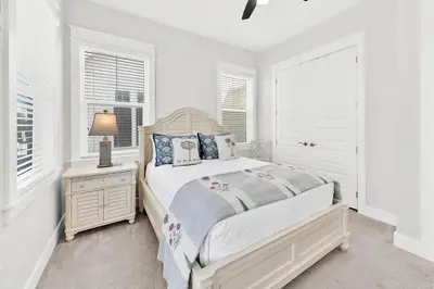 a white bedroom with a bed and a nightstand and windows at Town of Prominence 80C- The Wright Place in Santa Rosa Beach