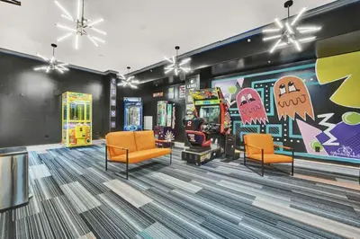 a gaming room with arcade games and orange chairs at Gulfcrest 206 in Panama City Beach