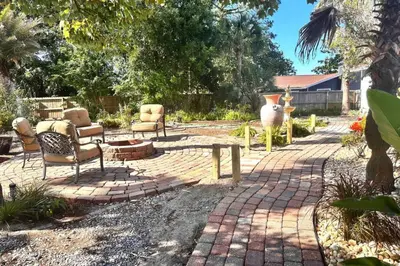 a garden with chairs and a brick patio at Shipwrecked - Private Pool Home, Game Room, 5 Min to Beach, Pets OK, & More! in Panama City Beach