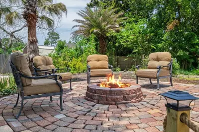 three chairs sitting around a fire pit in a yard at Shipwrecked - Private Pool Home, Game Room, 5 Min to Beach, Pets OK, & More! in Panama City Beach