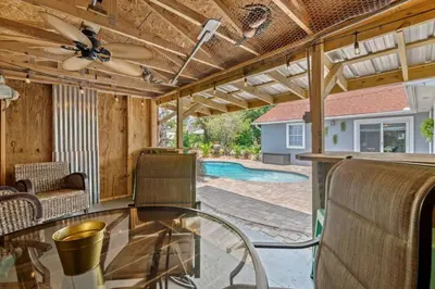 a screened in porch with a glass table and a ceiling fan at Shipwrecked - Private Pool Home, Game Room, 5 Min to Beach, Pets OK, & More! in Panama City Beach