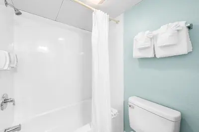 a bathroom with a toilet and a shower with towels at Boardwalk Beach Hotel in Panama City Beach