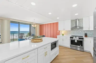 a kitchen with white cabinets and a view of the ocean at Edgewater Beach Resort #207 Tower 2 by Book That Condo in Panama City Beach