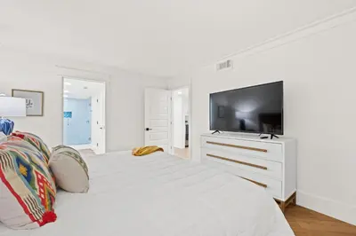 a white bedroom with a large bed with a tv on it at Edgewater Beach Resort #207 Tower 2 by Book That Condo in Panama City Beach