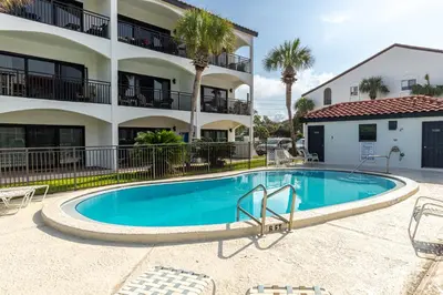 a swimming pool in front of a building with palm trees at Psalms in Santa Rosa Beach
