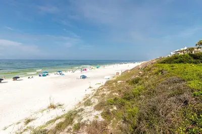 a beach with people and umbrellas and the ocean at Psalms in Santa Rosa Beach