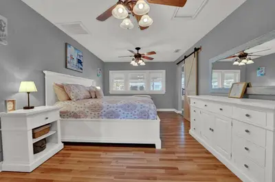 a bedroom with a white bed and a ceiling fan at Loaded House and Guest House w Game Room Gym in Panama City