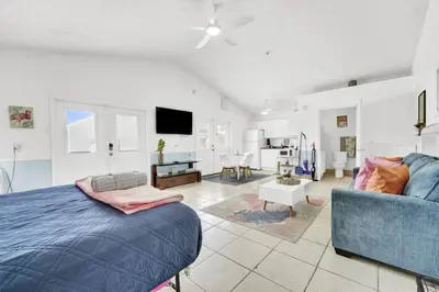 a bedroom with a bed and a living room with a couch at The Splash Pad Sleeps 13 w Pool Patio and Garage in Panama City