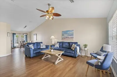 a living room with blue furniture and a ceiling fan at Escape to Paradise w Saltwater Pool 25 Min to PCB in Panama City