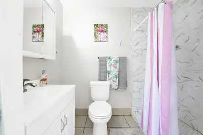 a bathroom with a white toilet and a pink shower curtain at Luxe Pool Casita w Saltwater Pool 25 Min to PCB in Panama City