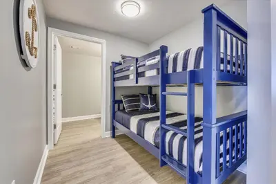 a blue bunk bed in a blue bedroom with wooden floors at Shores of Panama 1426 condo in Panama City Beach