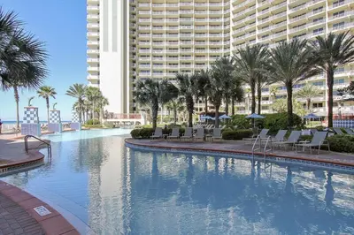 a large swimming pool with palm trees and a large building at Shores of Panama 1426 condo in Panama City Beach
