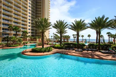 a pool at the resort with palm trees and buildings at Shores of Panama 1426 condo in Panama City Beach