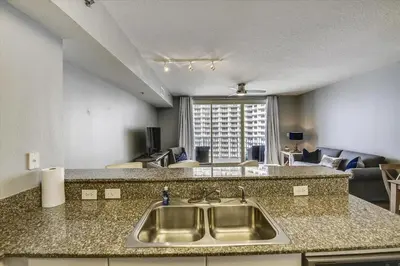 a kitchen with a sink and a living room at Shores of Panama 1426 condo in Panama City Beach