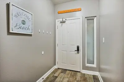 a hallway with a white door and a wooden floor at Shores of Panama 1708 condo in Panama City Beach